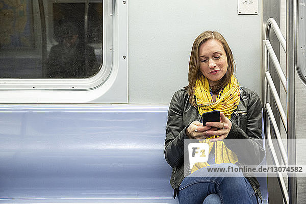 Frau benutzt Mobiltelefon während einer Zugfahrt
