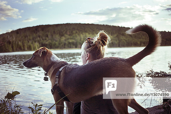 Rückansicht von Frau und Hund gegen See und Berg