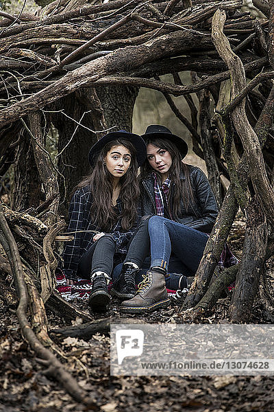 Porträt von Freundinnen  die inmitten von Wurzeln im Wald von Epping sitzen