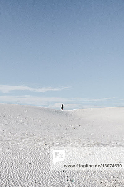 Distanzansicht einer Frau  die auf dem Feld gegen den Himmel am White Sands National Monument steht