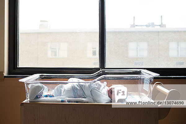 Kleiner Junge gähnt beim Schlafen im Kinderbett am Fenster im Krankenhaus