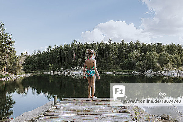 Rückansicht der Badebekleidung eines Mädchens  das auf einer Steintreppe am See steht
