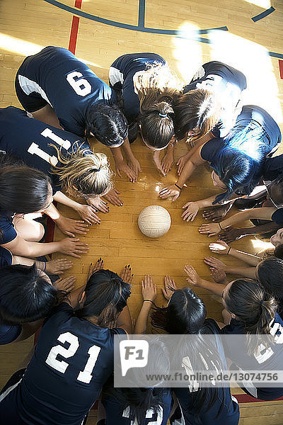 Hochwinkelansicht einer Volleyball-Mädchenmannschaft  die auf dem Boden kauert