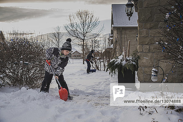 Brüder schaufeln Schnee vom Hinterhof