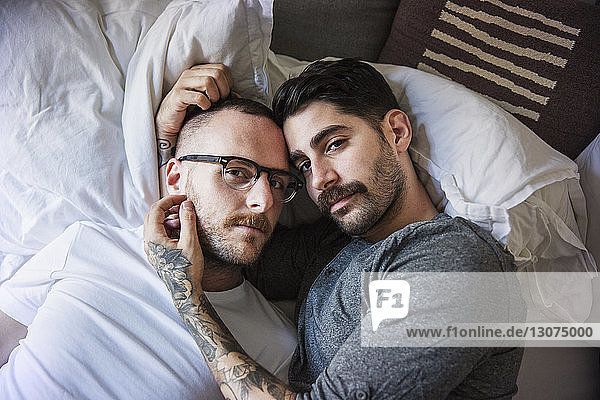 Hochwinkelporträt eines homosexuellen Paares  das zu Hause auf dem Bett liegt