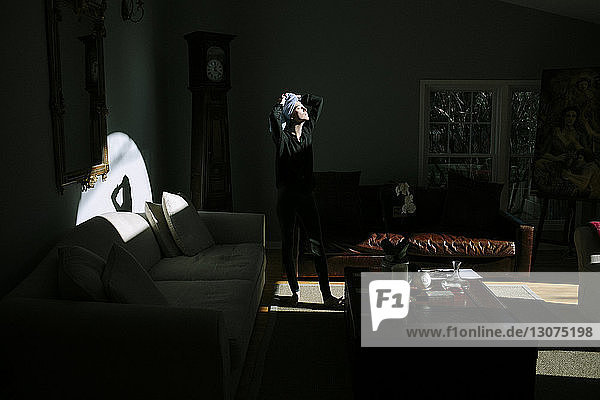 Frau mit Handtuch auf dem Kopf steht zu Hause in der Dunkelkammer