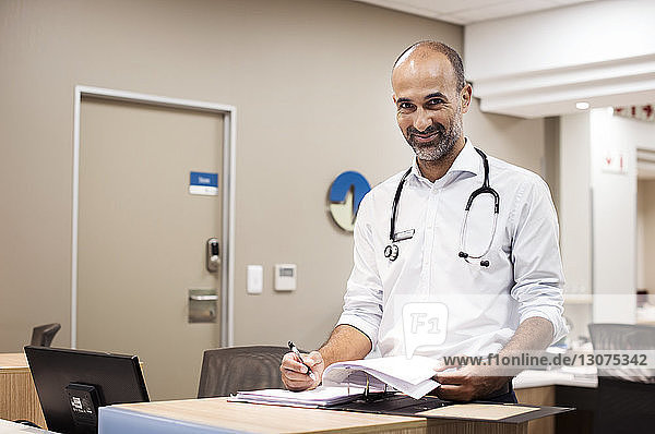 Porträt eines Arztes  der während seiner Arbeit im Krankenhaus Berichte erstellt