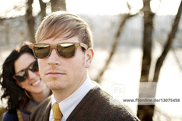 Couple wearing sunglasses against bare trees