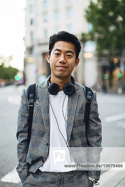Porträt eines selbstbewussten Geschäftsmannes mit Händen in den Taschen  der auf einem Fußweg in der Stadt steht