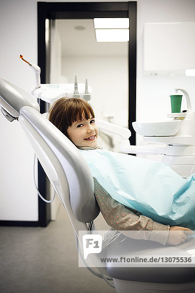Portrait of smiling girl sitting on dentist's chair at clinic