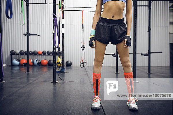 Low section of female athlete standing at gym