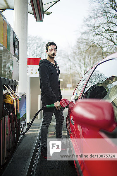 Porträt eines Mannes beim Tanken eines Autos an einer Tankstelle