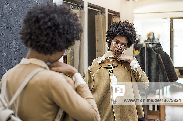 Frau wählt Jacke aus  während sie im Geschäft in den Spiegel schaut