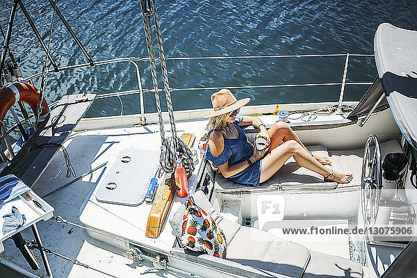 Hochwinkelaufnahme einer Frau  die sich auf einem Segelboot auf See entspannt