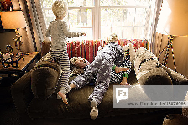 Brüder spielen zu Hause auf dem Sofa gegen das Fenster