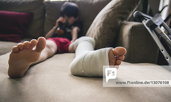 Boy with fractured leg sitting on sofa at home