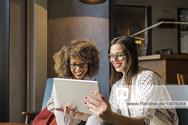 Happy businesswomen using tablet computer at hotel lobby