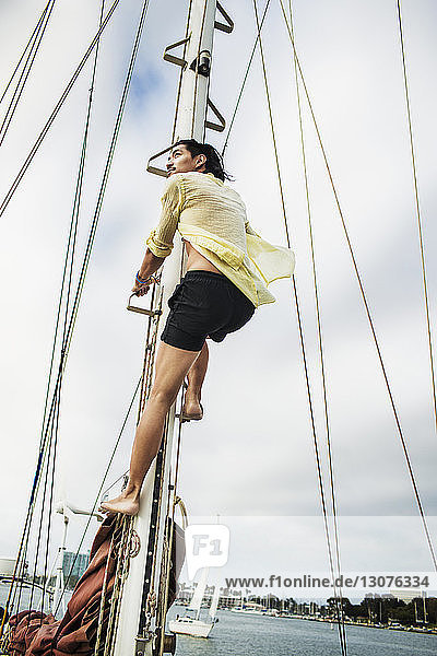 Niedrigwinkelansicht eines Mannes  der am Mast eines Segelbootes klettert