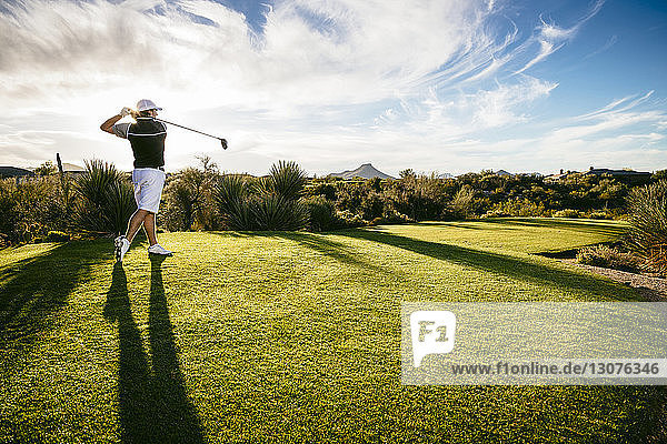 Full length of golfer playing on field against sky
