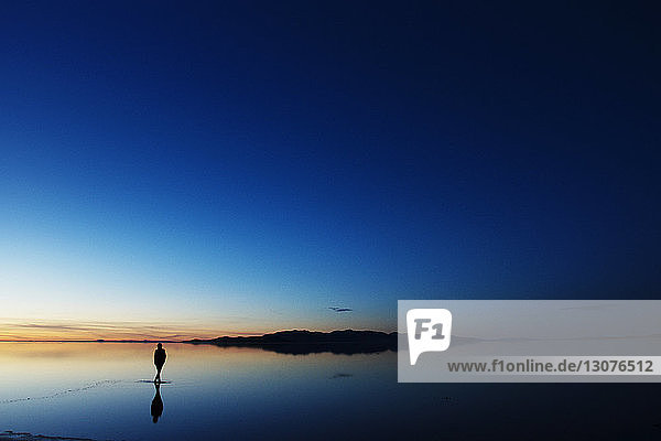 Silhouettenfrau steht bei Sonnenuntergang im Meer