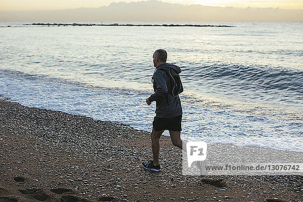 Hochwinkelaufnahme eines Mannes  der am Strand am Ufer joggt