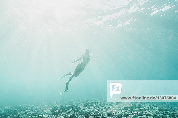 Tiefblick auf eine unterseeisch schwimmende Frau
