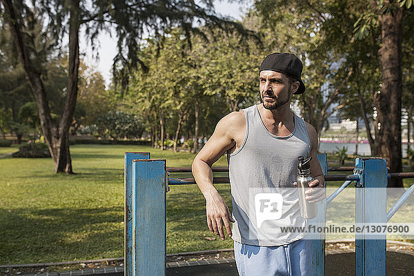 Man holding water bottle after exercising at park