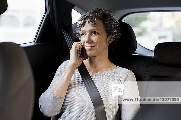 Reife Frau telefoniert im Auto sitzend per Handy