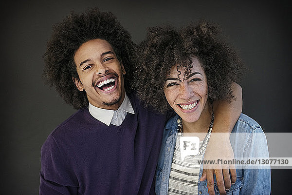 Porträt eines glücklichen Geschäftsmannes  der den Arm um eine Kollegin legt  vor schwarzem Hintergrund