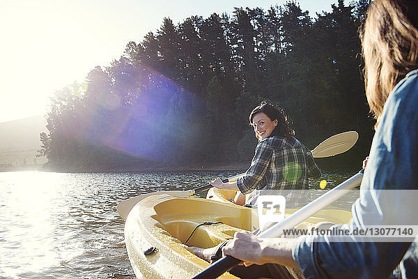 Glückliche Freundinnen  die bei Sonnenschein auf dem See Kajak fahren