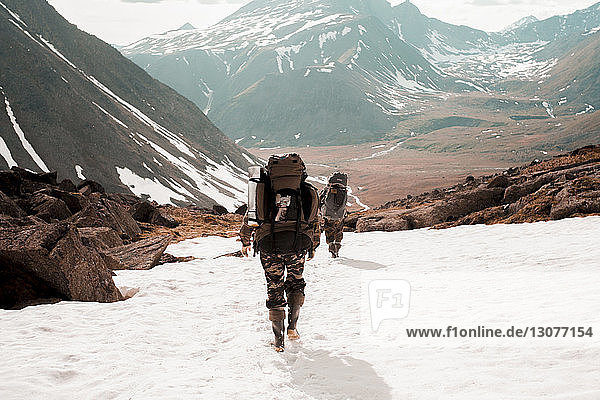 Rückansicht von Wanderern mit Rucksäcken  die im Winter in den Bergen wandern
