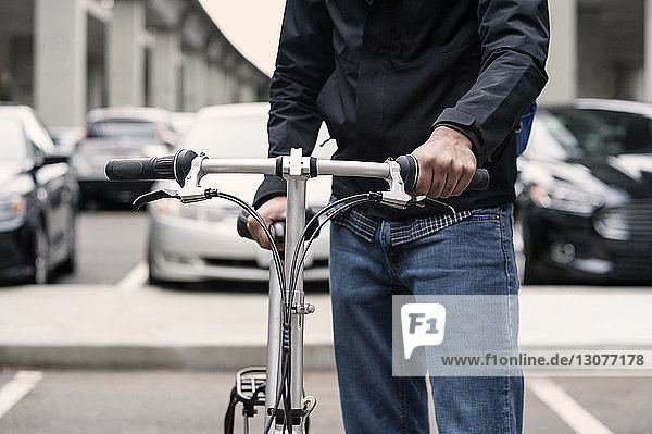 Mitten auf der Straße in der Stadt hält ein Geschäftsmann ein Fahrrad