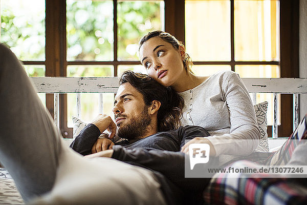 Thoughtful couple leaning on alcove window seat at home