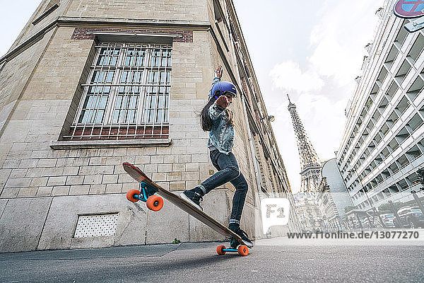 Niedriger Blickwinkel der Frau beim Skateboarden gegen den Eiffelturm