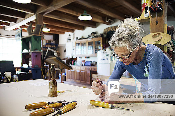 Konzentrierte Frau  die in der Werkstatt mit dem Meißel Holz bearbeitet