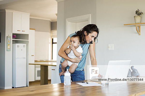 Frau benutzt Laptop-Computer  während sie mit ihrem Sohn zu Hause sitzt