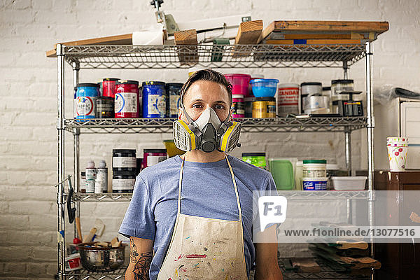 Porträt eines Arbeiters mit Schutzmaske in einer Werkstatt stehend