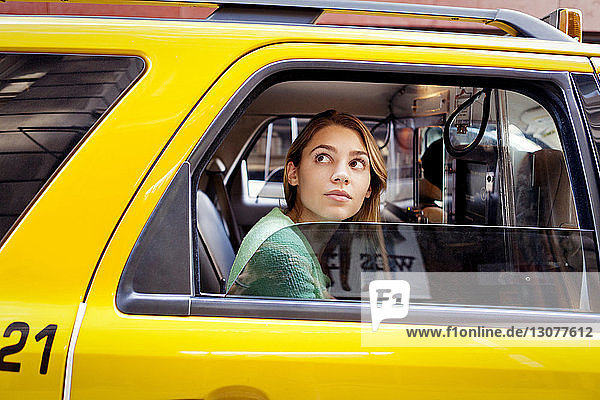 Frau schaut durch Fenster  während sie im Taxi in der Stadt sitzt