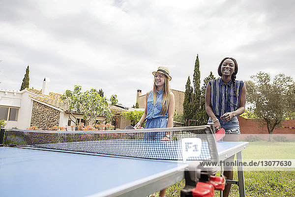 Glückliche Frauen spielen Tischtennis auf dem Hof