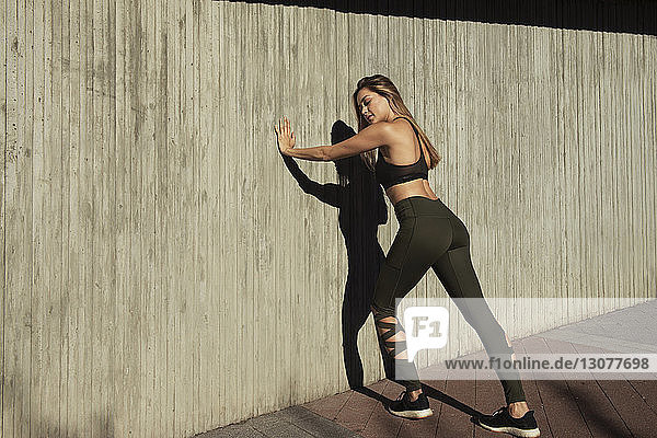 Junge Frau in voller Länge beim Training an der Mauer in der Stadt