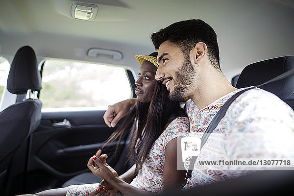 Glückliches multiethnisches Paar sitzt im Auto