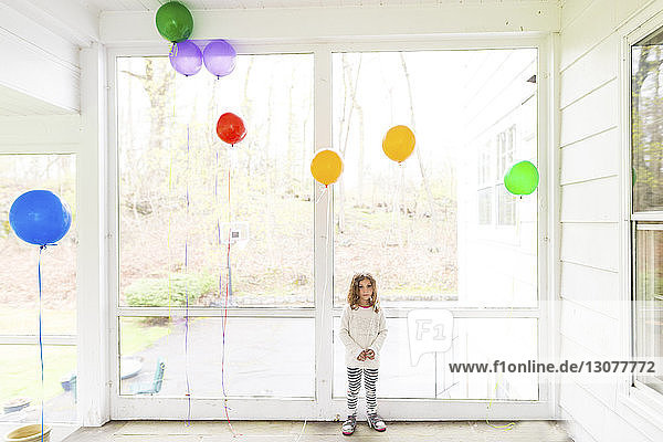 Full length of girl standing with balloons at home