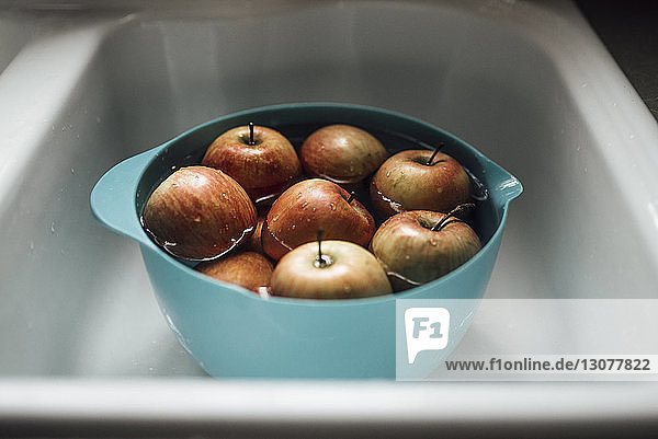 Hochwinkelansicht von Äpfeln mit Wasser in einer Schüssel auf der Küchenspüle
