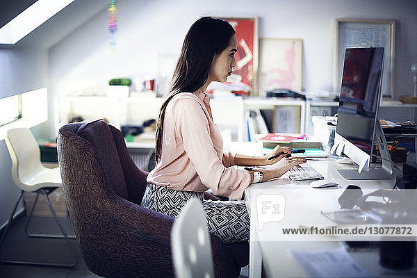 Businesswoman working on computer at desk in creative office