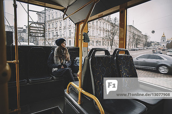 Nachdenkliche Frau schaut durch Fenster  während sie im Trolleybus reist