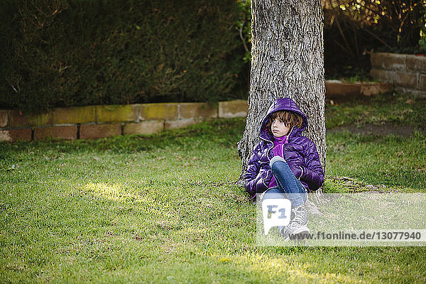 Nachdenkliches Mädchen entspannt sich auf Grasfeld bei einem Baum im Park