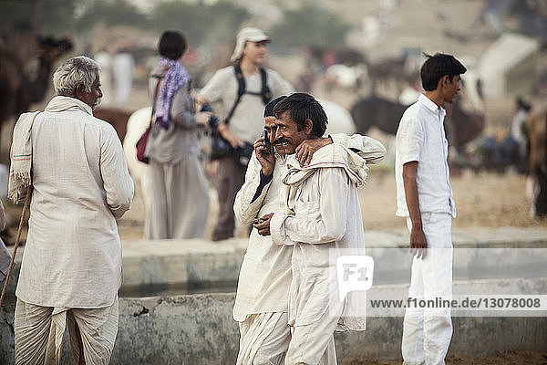 Man talking on phone while walking with friend at Pushkar Fair