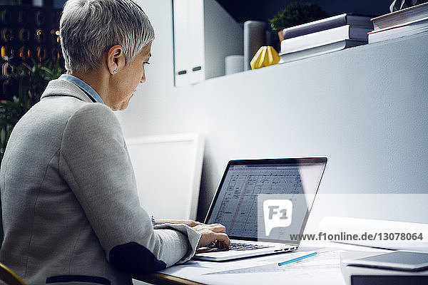 Serious architect using laptop at table in office