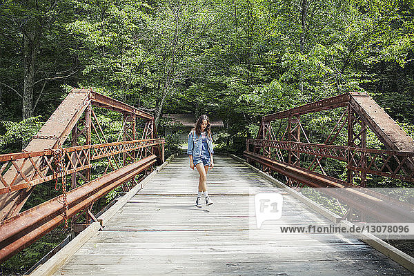 Frau geht auf Brücke gegen Bäume