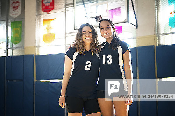 Portrait of smiling teenage girls standing in volleyball court